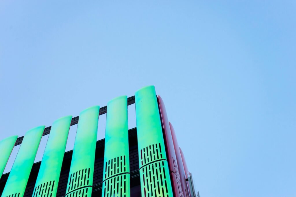 Vibrant green and red modern building facade with unique architecture against a clear blue sky.