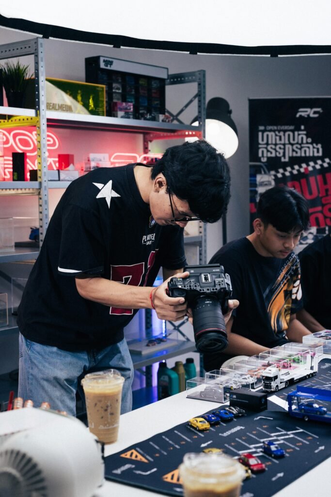 Photographer taking pictures of diecast car models in a studio setting in Phnom Penh.