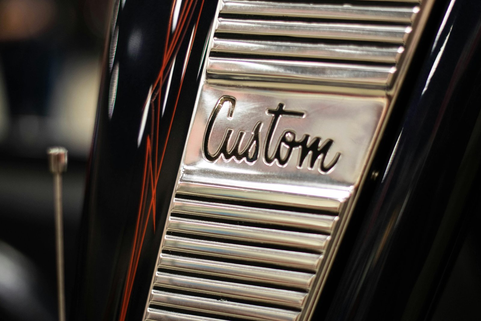 A close-up shot of a custom chrome detail on a classic car with pinstripe design.