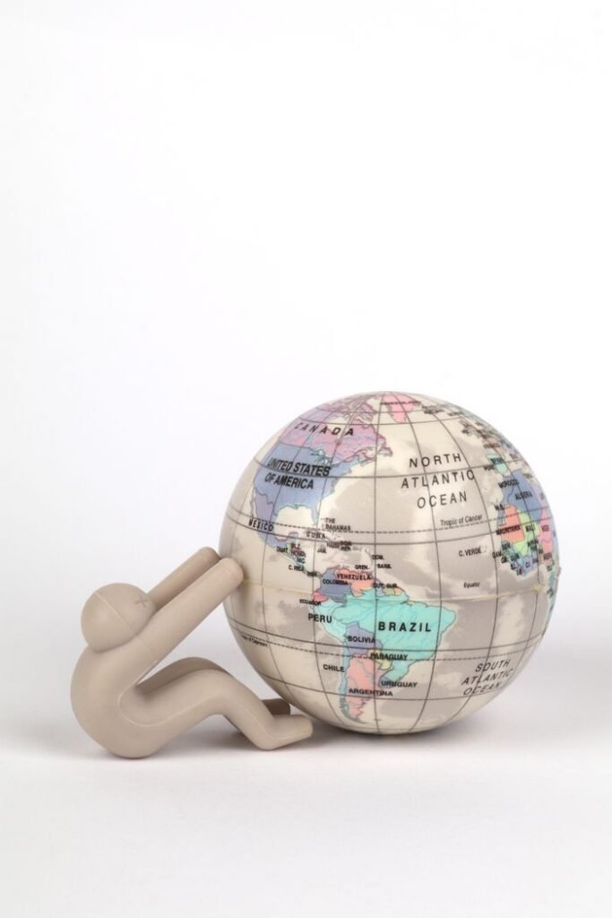 Abstract figurine pushing colorful globe symbolizing travel or global connection.